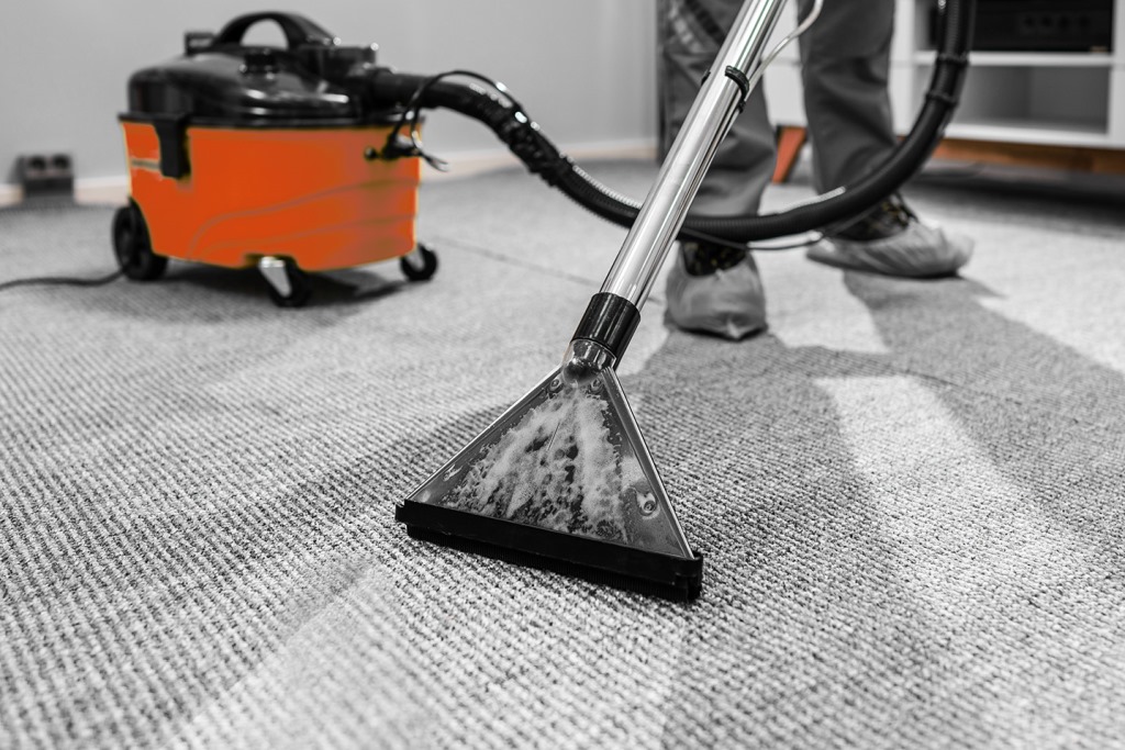 Person Cleaning Carpet With Vacuum Cleaner